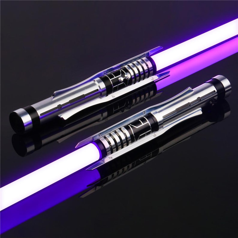 May include: Two silver and black lightsaber hilts with purple blades. The hilts have a textured, metallic finish and a series of black rings.