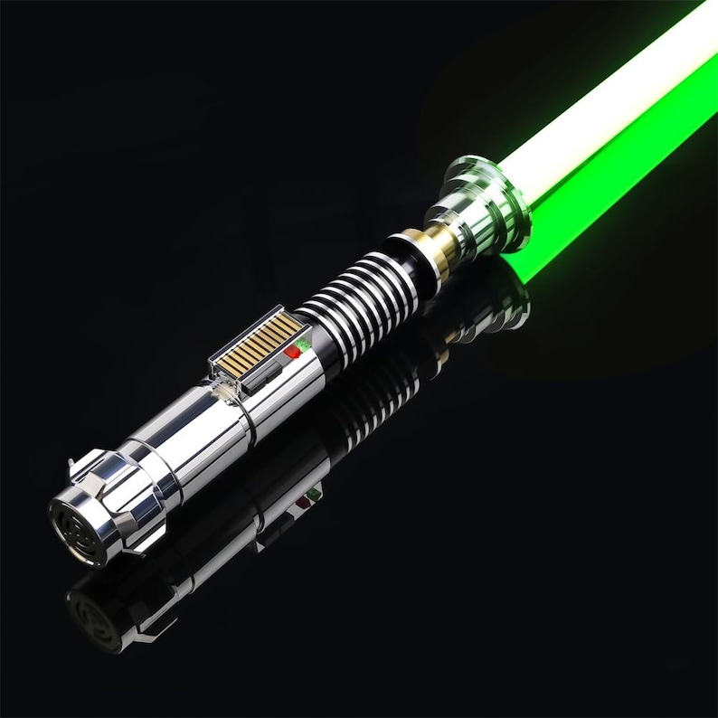 May include: A silver lightsaber with a green blade. The lightsaber has a black and silver handle with a gold accent. The blade is lit and glowing.