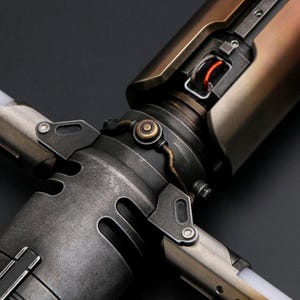 Puede incluir: Primer plano de una empu&ntilde;adura de sable de luz met&aacute;lica con un dise&ntilde;o industrial desgastado. La empu&ntilde;adura presenta una mezcla de tonos plateados, bronce y cobre, con intrincados detalles mec&aacute;nicos y un elemento rojo brillante.