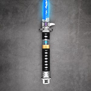 May include: A futuristic lightsaber with a glowing blue blade. The hilt is black with white diamond-shaped accents and a gold band. The design incorporates silver and purple metallic elements, creating a sleek, modern aesthetic.