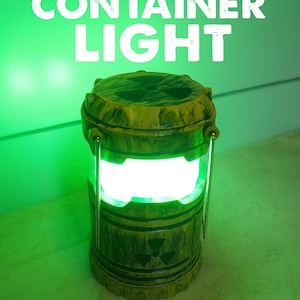 May include: A yellow and brown container-shaped light with the words "NUCLEAR CONTAINER LIGHT" in white. The light has a radiation symbol and a handle. The light emits a bright green glow.