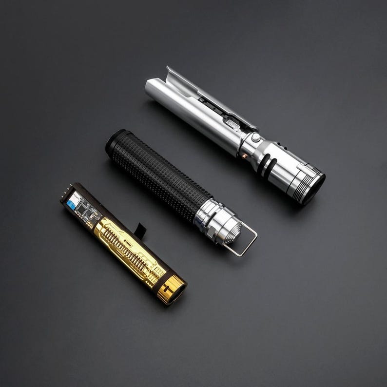 May include: Three lightsaber parts, including a silver lightsaber hilt, a black lightsaber grip, and a gold lightsaber battery pack.