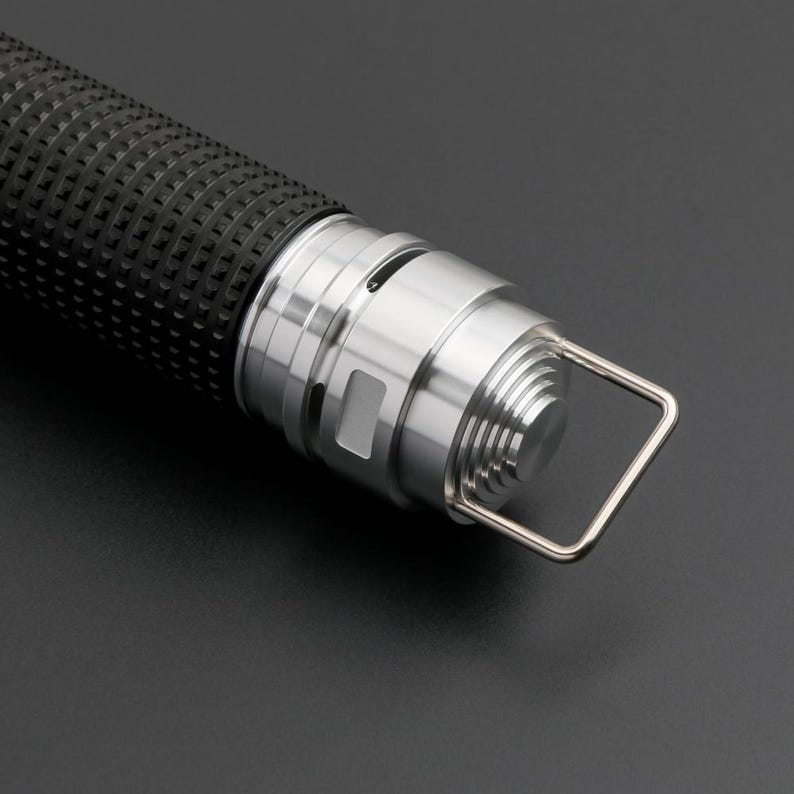 May include: A silver flashlight with a black rubber grip and a loop handle. The flashlight has a textured metal body and a small, round button on the side.