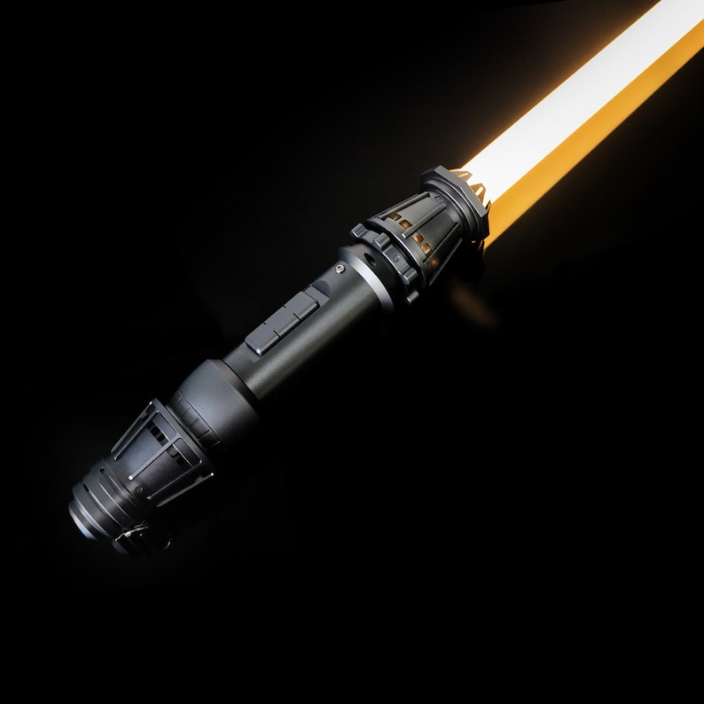 May include: A black lightsaber with a yellow blade. The lightsaber has a detailed hilt with buttons and a textured grip.