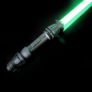 May include: A black lightsaber with a green blade. The lightsaber has a detailed handle with a textured grip.