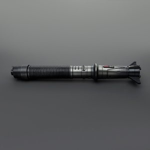 May include: A black lightsaber with a silver handle and a red button. The lightsaber has a textured, ribbed handle and a black blade.