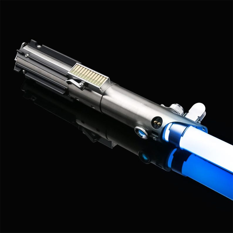 May include: A silver lightsaber with a blue blade. The lightsaber has a black handle with a silver button and a silver switch.