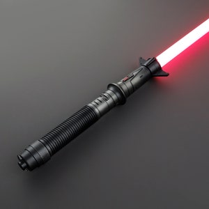 May include: A black lightsaber with a red blade. The lightsaber has a textured grip and a black hilt with a red button.