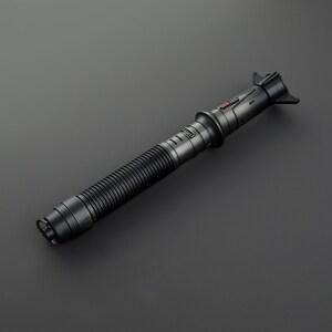 May include: A black lightsaber with a ribbed handle and a red button on the top. The lightsaber is made of metal and has a sleek, futuristic design.