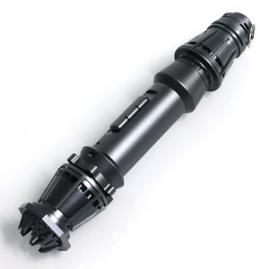 May include: A black lightsaber prop with a detailed handle and a textured emitter. The handle has a series of buttons and a textured grip.