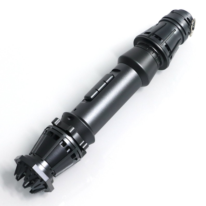 May include: A black lightsaber prop with a detailed handle and a textured emitter. The handle has a series of buttons and a textured grip.