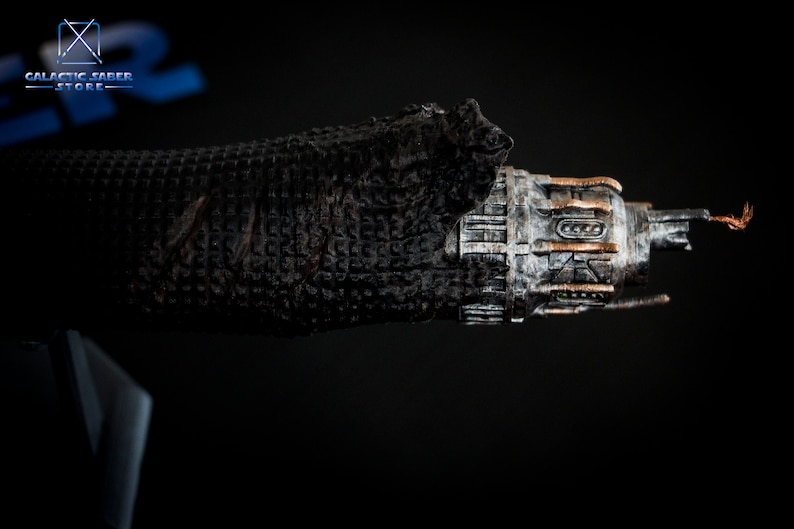 May include: A detailed model of a spaceship with a weathered, metallic finish. The spaceship has a long, cylindrical body with a pointed nose and a series of small, rectangular windows. The model is partially covered in a black, textured material.