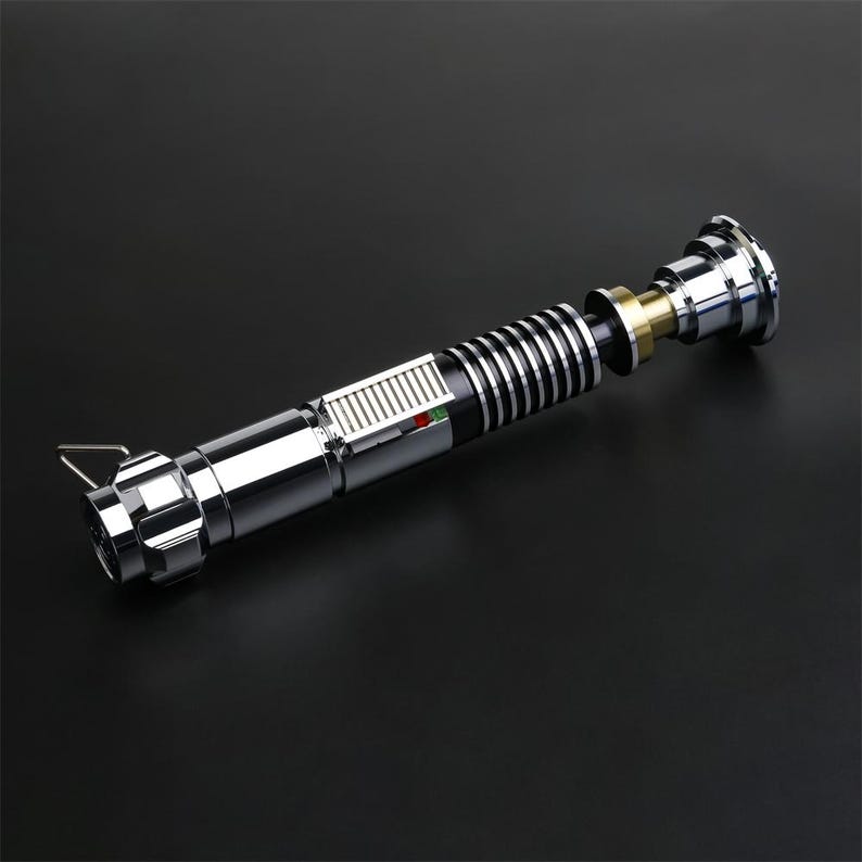 May include: A disassembled silver lightsaber with a black and silver handle, a green and red light, and a gold and silver connector.