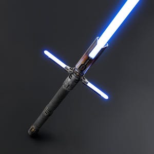 Puede incluir: Imagen detallada de un sable de luz azul con dise&ntilde;o de guarda cruzada. El mango tiene un agarre texturizado gris oscuro y un emisor marr&oacute;n y plateado. La hoja principal y las hojas de la guarda emiten un brillo azul brillante sobre un fondo oscuro.