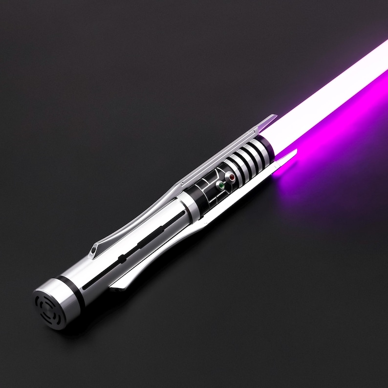 May include: A silver lightsaber with a purple blade. The lightsaber has a black and silver handle with a green and red button.