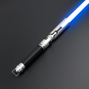 May include: A silver and black lightsaber with a blue blade. The lightsaber is switched on and the blade is glowing.