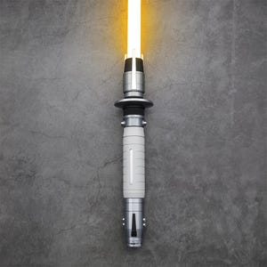 Peut inclure: Un sabre laser argent&eacute; avec une lame blanche, allum&eacute; et brillant sur un fond gris.