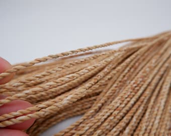 May include: A close-up of a bundle of natural fiber rope, showing the individual strands of the rope. The rope is a light brown color and has a slightly rough texture.