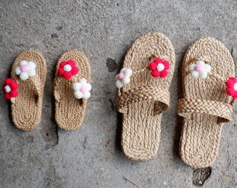 May include: Three pairs of woven straw sandals with crocheted flower embellishments in red, white, and pink. The sandals are arranged in a row from smallest to largest.