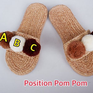 May include: A pair of brown woven slippers with three pom-poms on each slipper. The pom-poms are brown, white, and dark brown. The pom-poms are labeled A, B, and C.