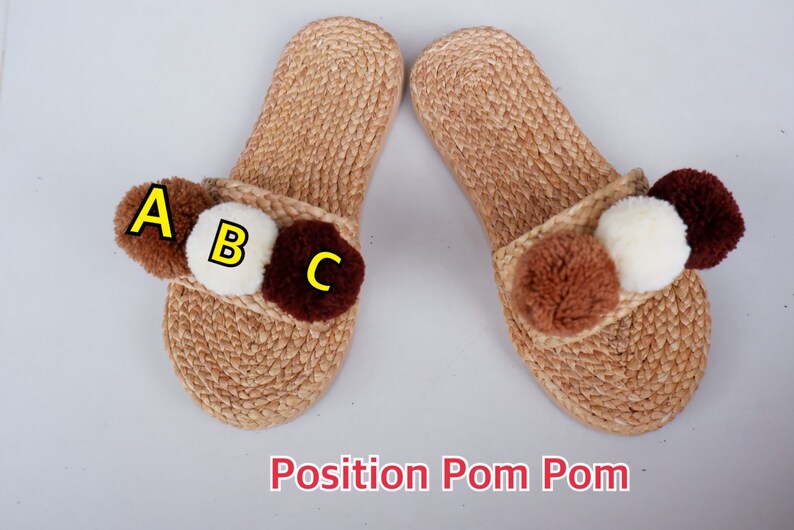 May include: A pair of brown woven slippers with three pom-poms on each slipper. The pom-poms are brown, white, and dark brown. The pom-poms are labeled A, B, and C.
