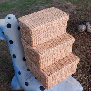 May include: Three woven storage baskets stacked on top of each other. The baskets are made of natural materials and have a light brown color.