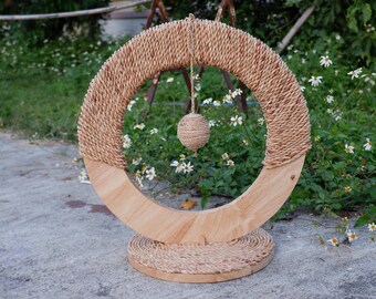 May include: A wooden cat toy with a circular base and a ring of woven rope. A dangling ball of woven rope hangs from the ring.