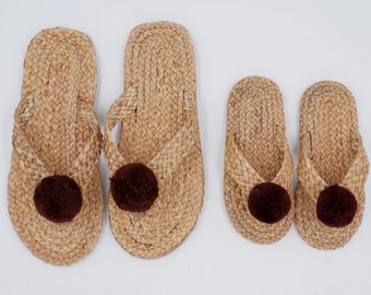 May include: Three pairs of woven straw sandals with brown pom-poms. The sandals are in different sizes.