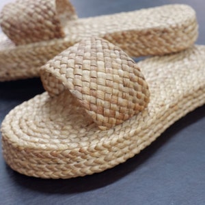 May include: A pair of woven straw sandals with a simple design. The sandals are made of natural materials and have a comfortable, casual look.