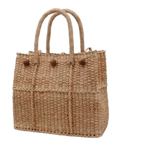 K&ouml;nnte beinhalten: Eine geflochtene Strohtasche mit braunen Holz-Knopf-Akzenten. Die Tasche hat zwei Henkel und eine breite &Ouml;ffnung.