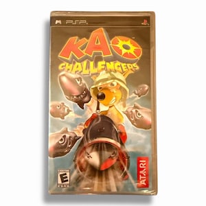 May include: A PSP video game case for "Kao Challengers" featuring a cartoon kangaroo character wearing a safari hat. The cover art includes the game title in red and yellow, along with images of sharks and the Atari logo.