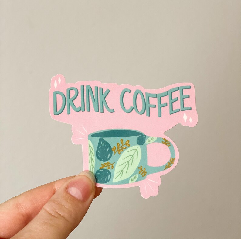 May include: Pink sticker with the text "DRINK COFFEE" and a blue coffee mug with a green and gold leaf pattern.