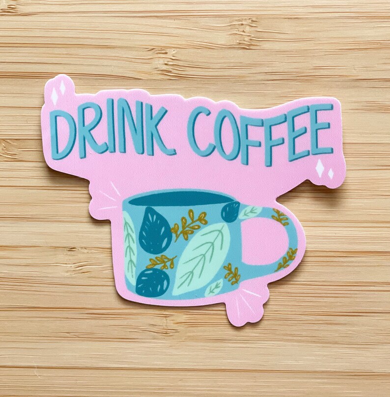 May include: Pink sticker with the text "DRINK COFFEE" in blue lettering. A blue and green coffee mug with a leafy design is below the text.
