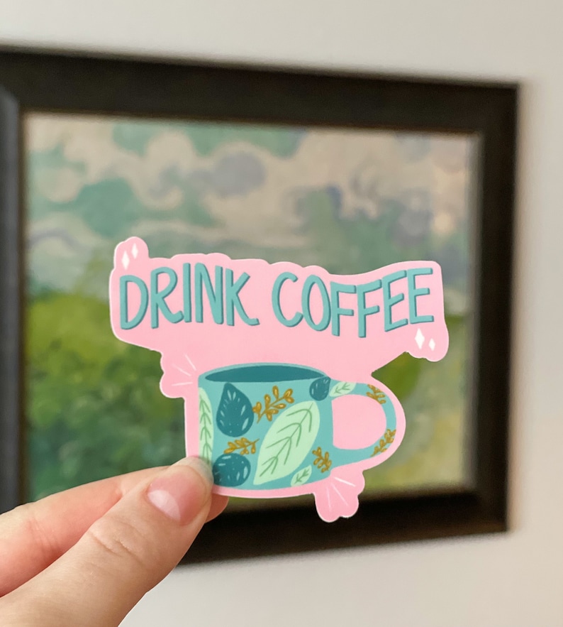 May include: Pink sticker with the text "DRINK COFFEE" in teal lettering. A teal coffee mug with a leafy pattern is below the text.