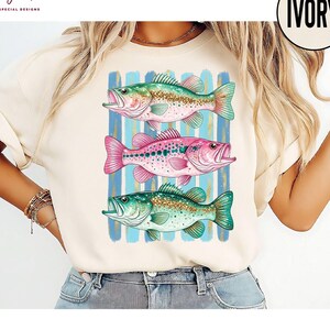 A woman wearing a white t-shirt with a graphic design of three colorful fish.