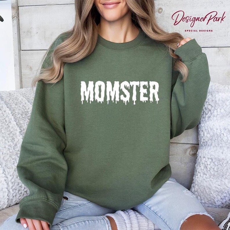 A woman wearing a green sweatshirt with the word "MOMSTER" printed on it.