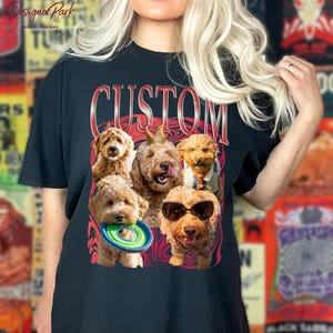 A woman wearing a black t-shirt with a graphic design featuring a group of dogs, including a golden retriever, a poodle, and a dachshund, along with a frisbee.