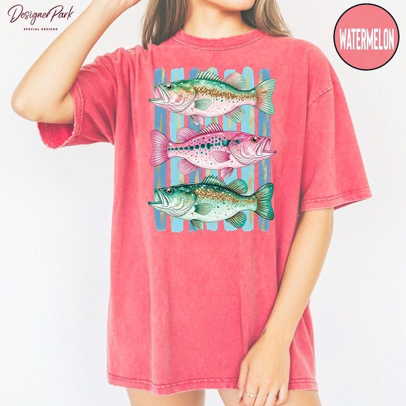 A woman wearing a pink t-shirt with a graphic design of three colorful fish.