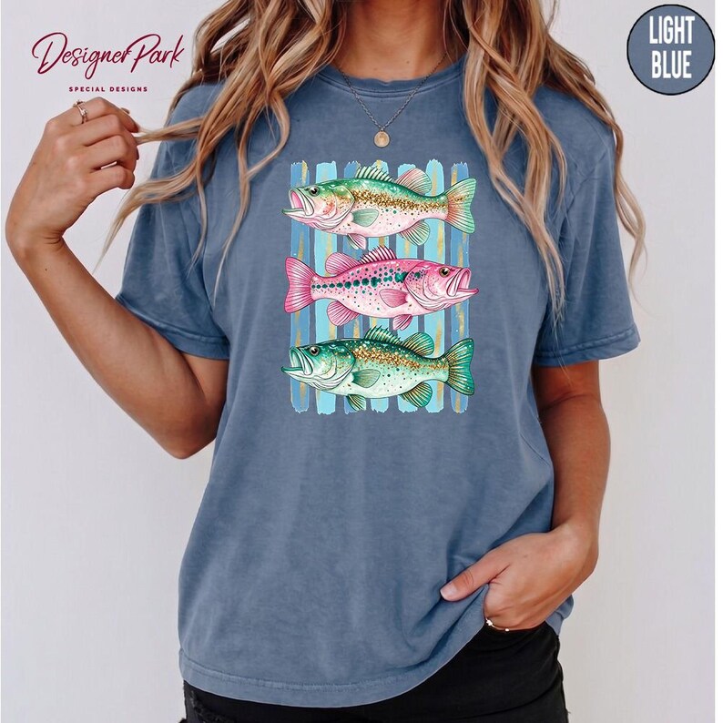 A woman wearing a blue t-shirt with a graphic design of three colorful fish.