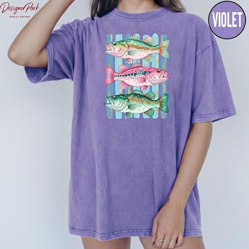A person wearing a purple t-shirt with a graphic design of three colorful fish.