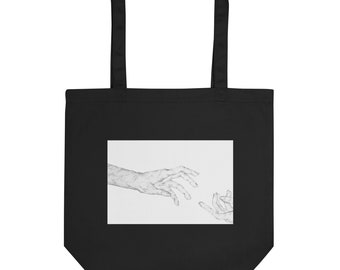 May include: Black tote bag with a white rectangle featuring a black and white line drawing of two hands reaching towards each other.
