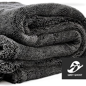 May include: A stack of dark gray microfiber towels with a textured, plush surface. The towels are folded and stacked, showcasing their absorbent material. The Grey Ghost logo is visible in the corner.