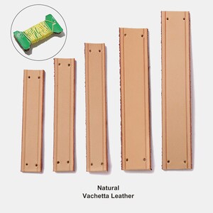 Peut inclure: Cinq bandes rectangulaires en cuir Vachetta naturel dispos&eacute;es par longueur croissante, chacune avec deux trous pr&eacute;-perc&eacute;s aux extr&eacute;mit&eacute;s et des lignes doubles surpiqu&eacute;es. Une petite bobine verte avec du fil jaune est incluse en haut &agrave; gauche.