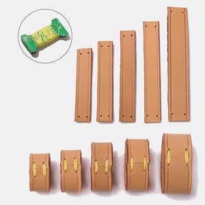 Peut inclure: Cinq bandes de cuir beige rectangulaires avec des trous pr&eacute;-perc&eacute;s &agrave; chaque extr&eacute;mit&eacute;, dispos&eacute;es verticalement. En dessous, cinq bandes de cuir assorties sont boucl&eacute;es et fix&eacute;es avec du fil jaune. Une bobine verte avec du fil jaune est encercl&eacute;e.