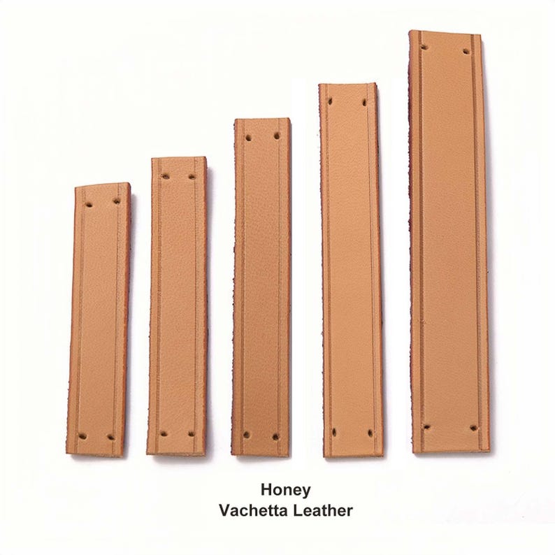 Peut inclure: Cinq bandes rectangulaires en cuir vachette couleur miel dispos&eacute;es par longueur croissante. Chaque bande pr&eacute;sente deux lignes verticales en relief et deux trous pr&eacute;-perc&eacute;s aux extr&eacute;mit&eacute;s. Le texte indique Honey Vachetta Leather.