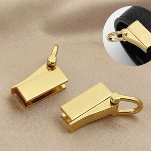 May include: Three gold-toned metal clasps for attaching to a bag or strap. The clasps have a rectangular shape with a small loop on one end and a hook on the other.