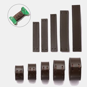 Peut inclure: Un ensemble de cinq bandes de cuir rectangulaires marron fonc&eacute; avec des trous pr&eacute;-perc&eacute;s, cinq bracelets en cuir marron fonc&eacute; assortis fix&eacute;s par du fil marron, et une petite bobine en carton vert enroul&eacute;e de fil marron.