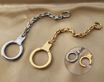 Pode incluir: Dois chaveiros com elos de metal prata e ouro. Um chaveiro tem um anel prateado e o outro um anel dourado.