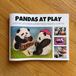 Op de afbeelding: Een kleurboek getiteld "PANDAS AT PLAY" met illustraties van panda's. De omslag toont twee panda's, een die leest en de andere met een hoed. Aanvullende panda-illustraties worden aan de rechterkant van de omslag weergegeven.
