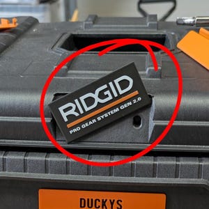 May include: Black toolbox with the brand name "RIDGID" and "PRO GEAR SYSTEM GEN 2.0" printed on a black and orange label. The toolbox also has an orange label that says "DUCKYS".